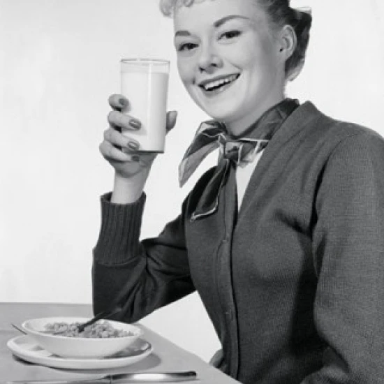 Portrait of a young woman eating breakfast Poster Print (24 x 36)