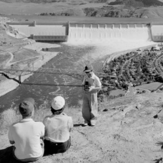 Boy taking photo of parents  dam in the background Poster Print (18 x 24)
