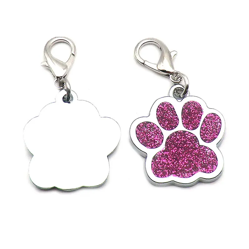 Two durable metal pet tags with lobster clasps, featuring paw-shaped charms. One charm is plain silver, and the other showcases a pink glitter design on the front. Perfect for personalized paw ID tags and available for wholesale pet tag orders, such as The Stuff Box's High Quality Engravable Pendants for Dogs and Cats 100Pcs.