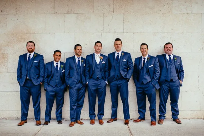 16.-Groom-with-groomsmen-standing-with-their-hands-in-their-pockets-wearing-blue-suits-