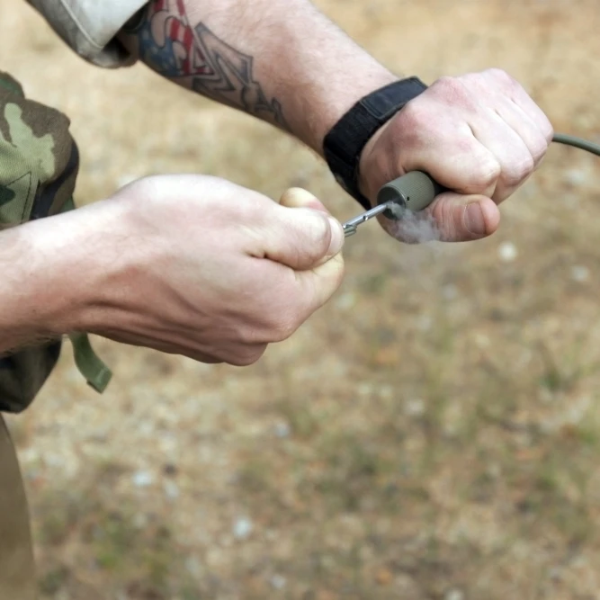 A soldier pulls a detonation cord igniter to start a reaction detonating C-4 explosives Poster Print (16 x 11)