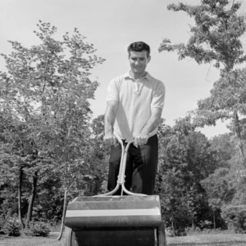 Low angle view of a young man fertilizing a lawn Poster Print (24 x 36)