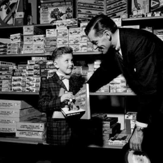 Shop assistant serving boy in toy shop Poster Print (18 x 24)