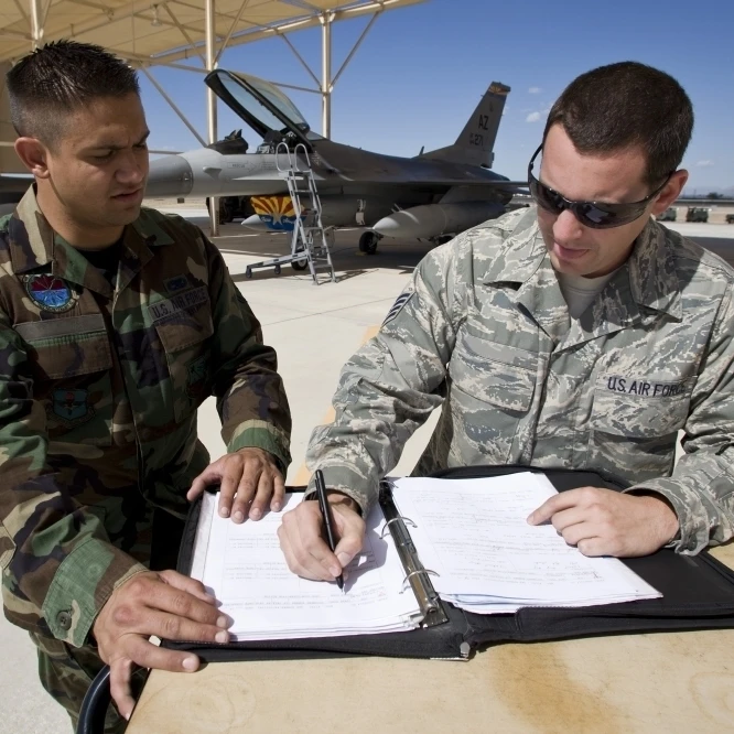Two F-16 crew chiefs go over paperwork between missions Poster Print (17 x 11)