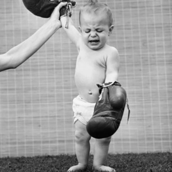 Person's hand raising a baby's hand wearing boxing gloves Poster Print (18 x 24)