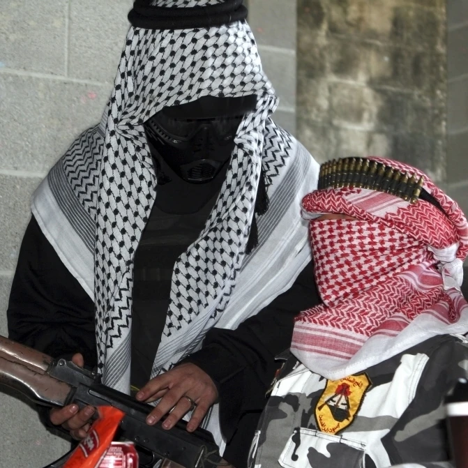 A role-playing enemy aggressor arms a dummy with a simulated AK-47 rifle Poster Print (33 x 22)