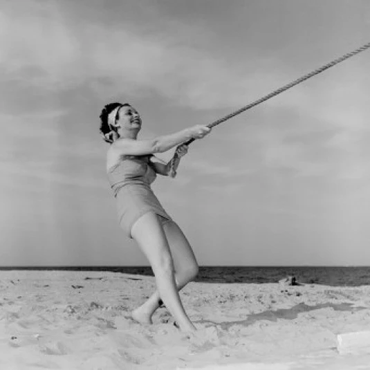 Young happy woman pulling rope at beach Poster Print (24 x 36)
