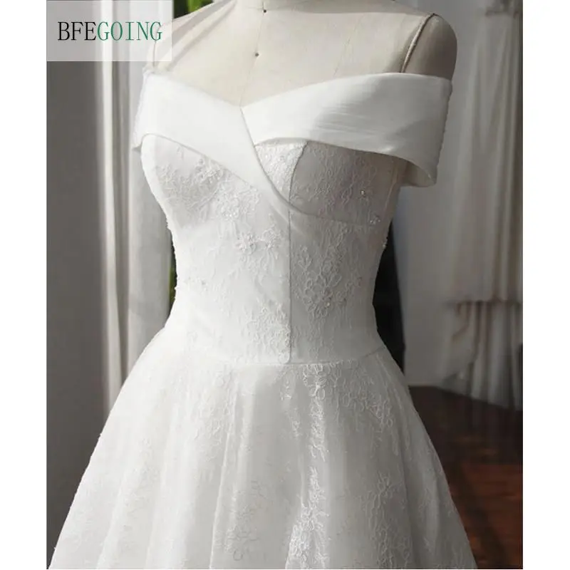 Свадебное платье трапециевидной формы длиной до середины икры, расшитое бисером и украшенное асимметричным драпированным вырезом, выполненное на заказ