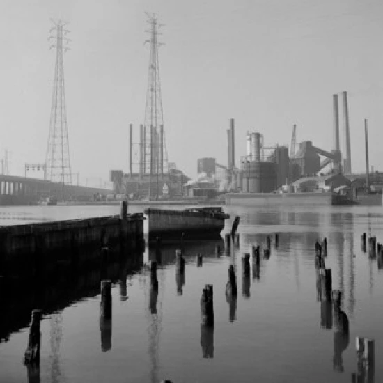 Moored rowing boat  factory in the background Poster Print (18 x 24)