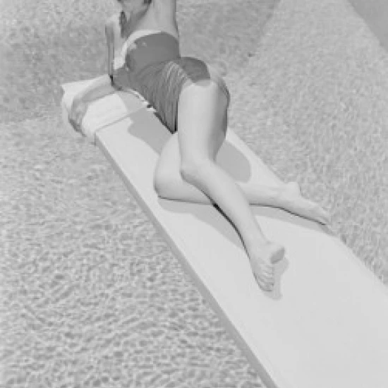 Young woman in swimwear lying on diving board Poster Print (24 x 36)
