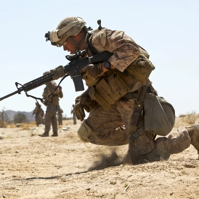 Rifleman kneels to the ground while conducting buddy rushes Poster Print (17 x 11)