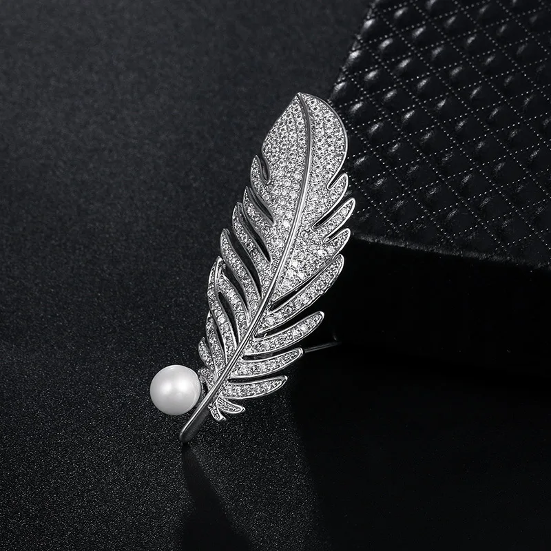 Брошь серебристая с жемчужиной. Брошь для перьев из гильзы. Брошь перо с жемчугом. Украшения на белом фоне. Жемчуг перо.