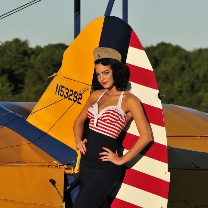 1940's style pin-up girl leaning on the tail fin of a Stearman biplane Poster Print (17 x 11)