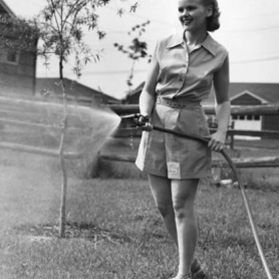 Teenage girl watering lawn Poster Print (18 x 24)
