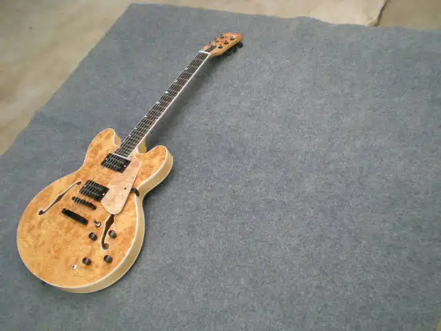 

Custom 6 string jazz electric guitar with scabbed veneer, wood color, black accessories, double F hole hollow body.