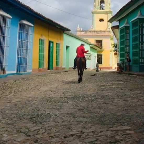 Cobblestone street with cowboy on horse  Trinidad  Cuba Poster Print by Bill Bachmann (22 x 34)