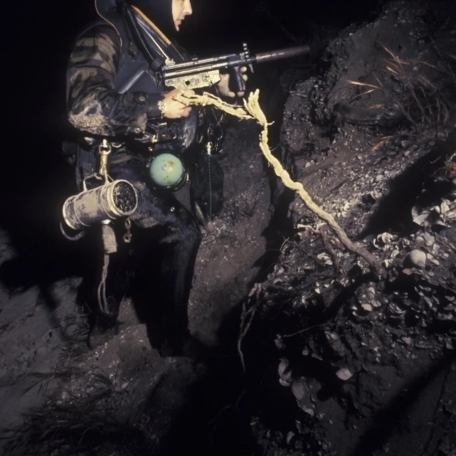 A Navy SEAL crosses the beach at night fully armed Poster Print (11 x 17)