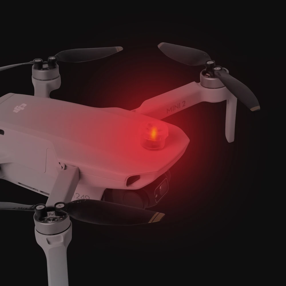Drone DJI équipé de feux de navigation LED rouges et verts, prêt à voler de nuit, vue de dessus.