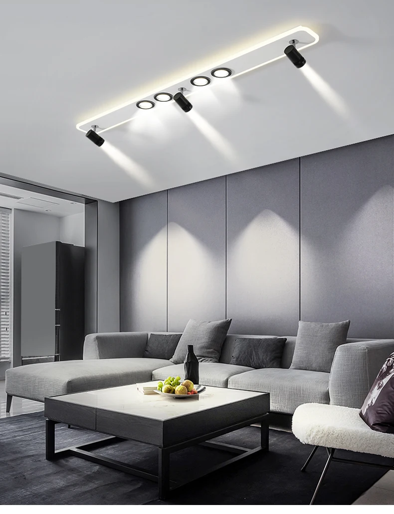 A modern living room with a grey couch, coffee table, and track ceiling light creating a sophisticated ambiance.