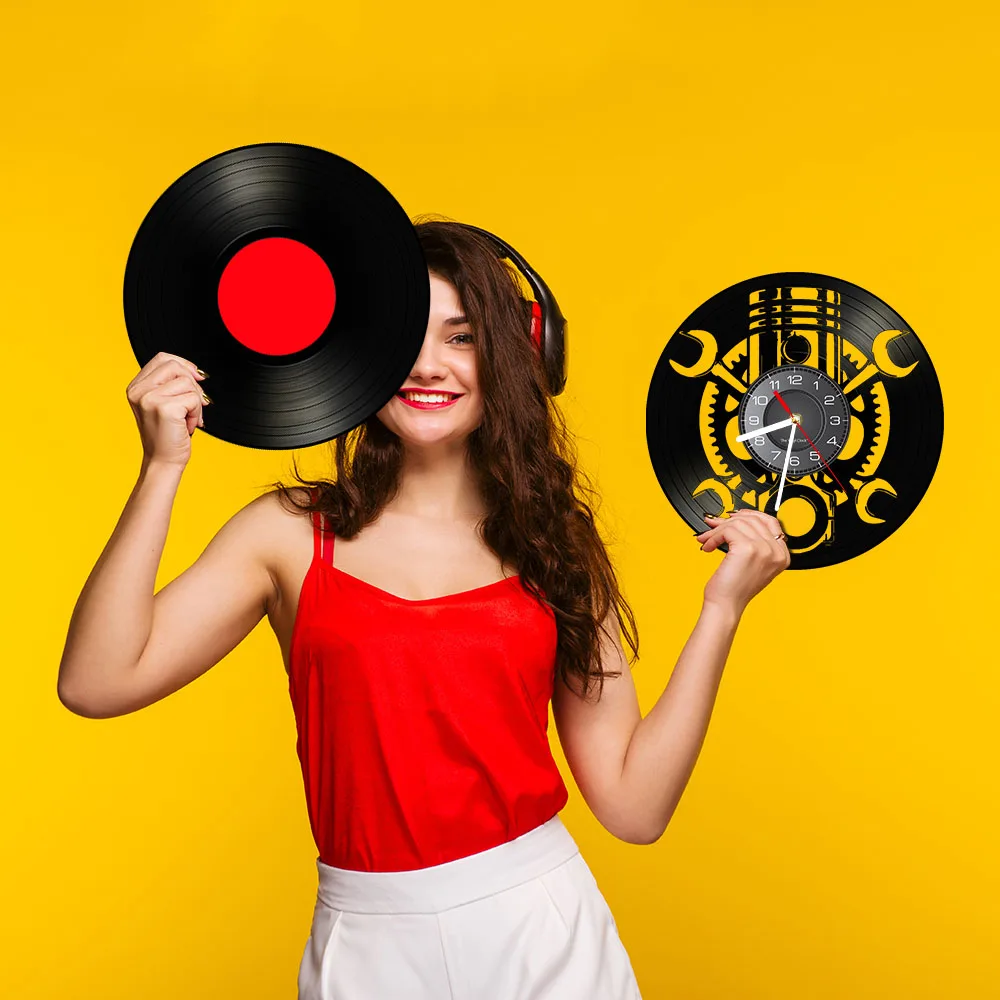 A woman in a red top showcases a Black Record Wall Clock against a vibrant yellow background.