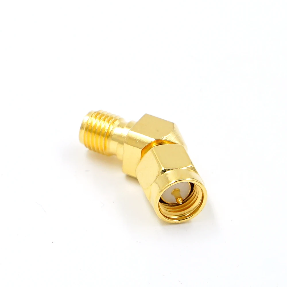 Adaptateur d'antenne FPV SMA mâle vers RP SMA femelle plaqué or, posé sur une surface réfléchissante.