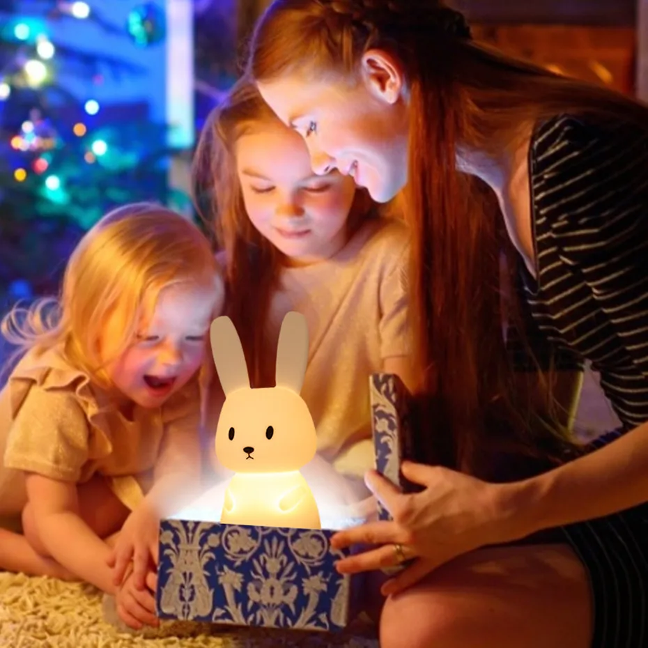 A woman and two children looking at an adorable box with a bunny inside.