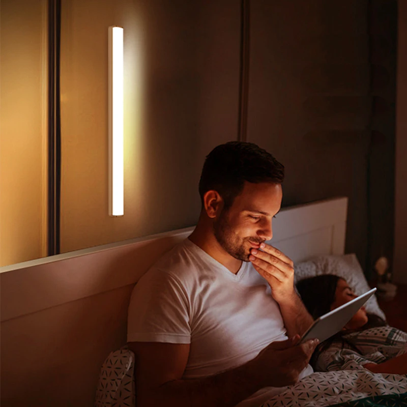 A man is reading under a Motion Sensor Light Wireless LED from the Brookline shop in bed.