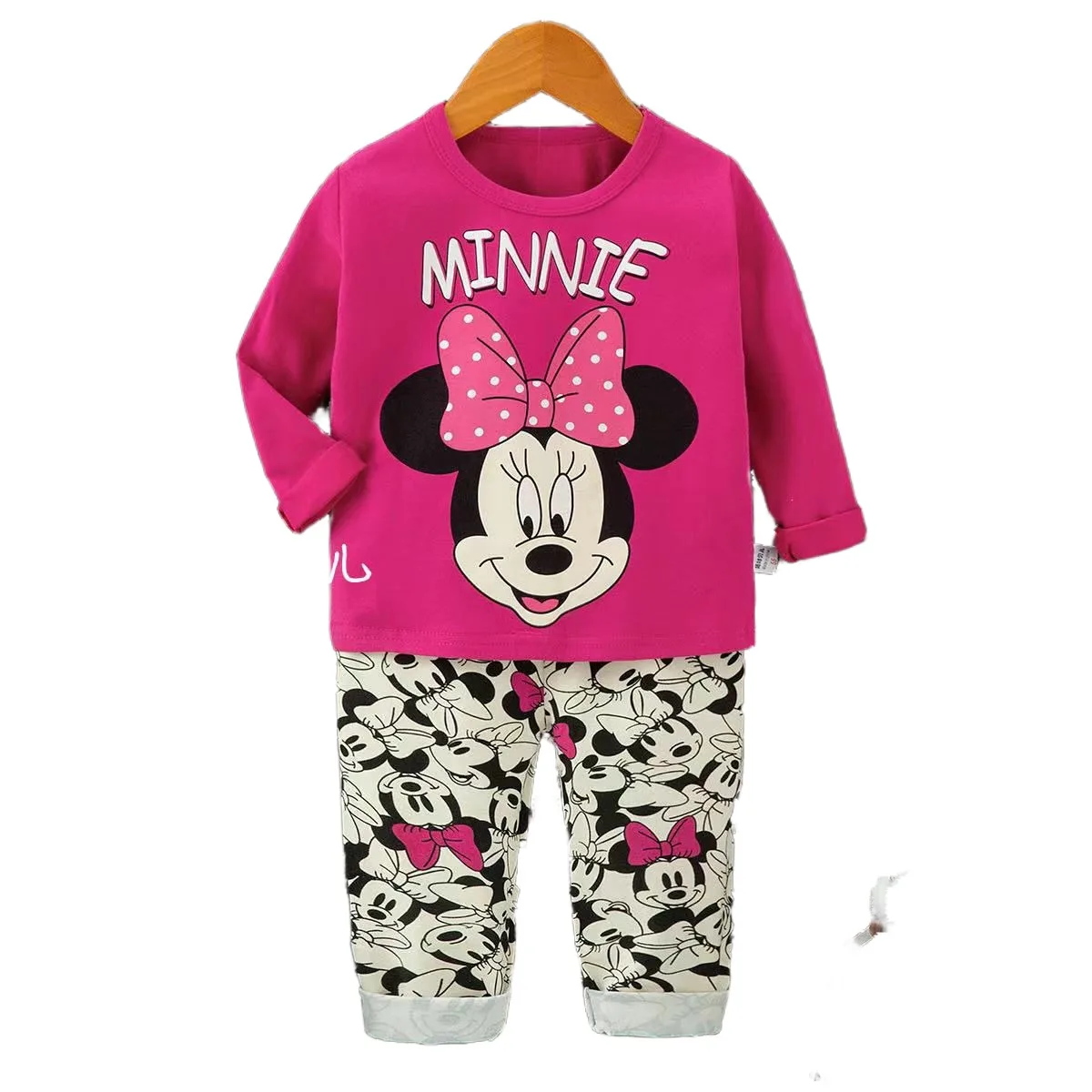 Baby wearing a Minnie Mouse outfit set with matching top and shorts, smiling while playing outdoors.