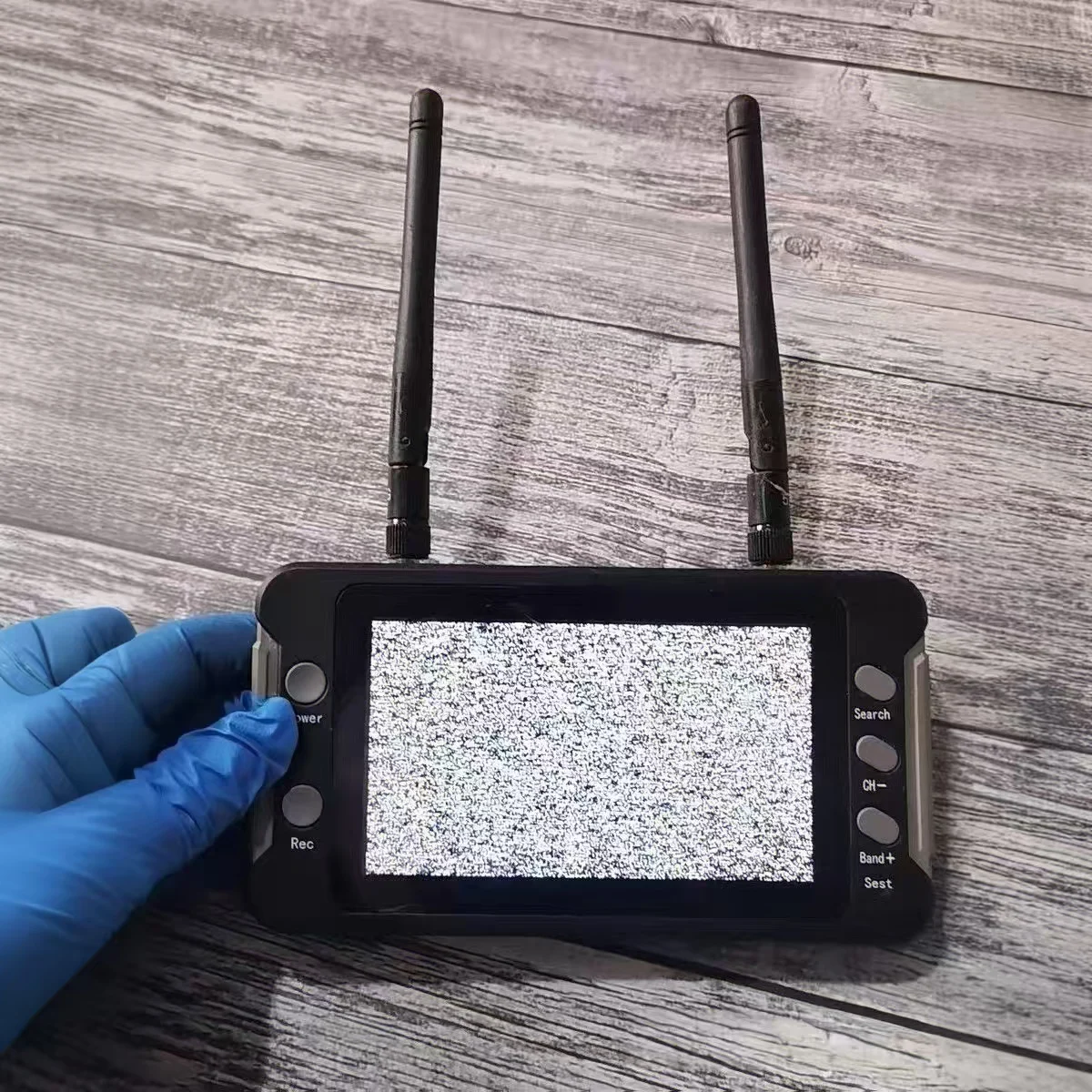 Moniteur FPV 5.8G 40CH avec DVR posé sur une table, câbles d'alimentation et antennes connectés, prêt pour drone FPV.
