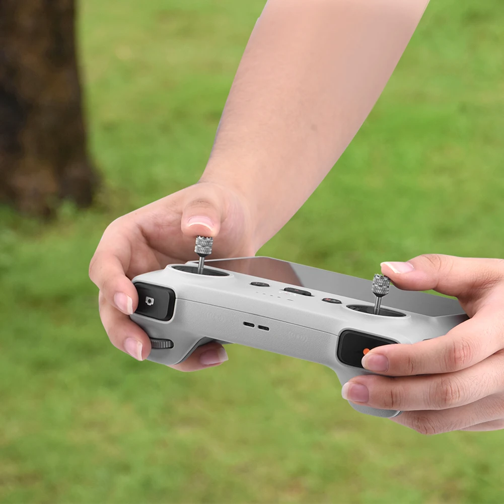 Deux joysticks de pouce en alliage d'aluminium pour télécommande DJI Mini 3 Pro RC, l'un or et l'autre argent, sur fond rouge