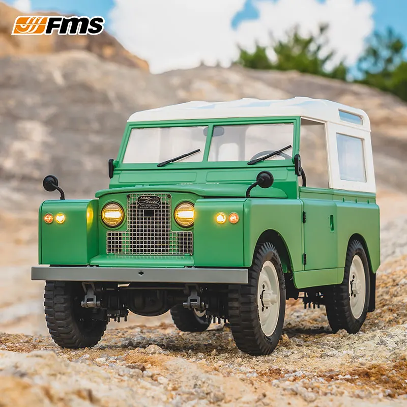 Le FMS 1/12 Land II RC Rover 4x4 en action, soulevant de la poussière sur un chemin de terre.