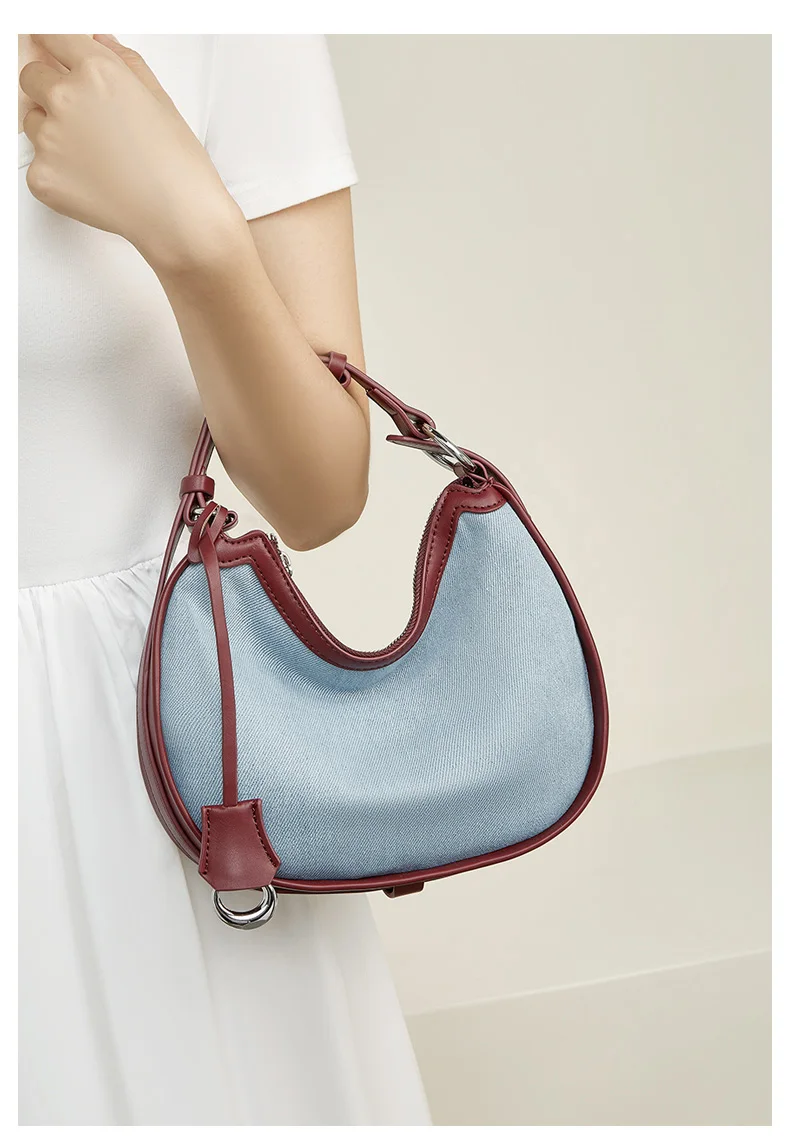 Woman carrying half moon shoulder bag made of denim with genuine leather trim – casual and stylish design for daily use.