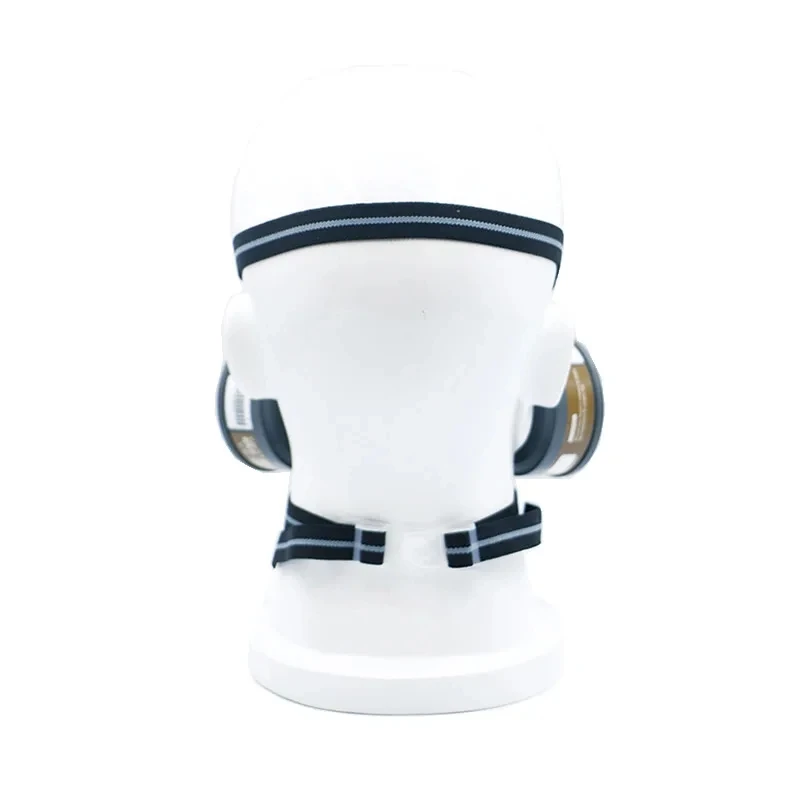 Demi-masque respirateur anti-poussière double filtres en main, prêt à être utilisé pour protection contre particules.