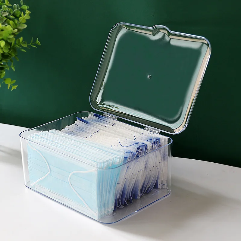 Boîte de rangement pour masques covid posée sur un bureau, à côté d'autres accessoires de protection.