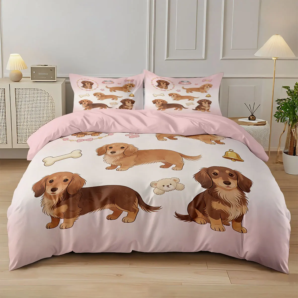 A 3-piece blush pink bedding set featuring a cute cartoon print of Dachshund sausage dog puppies on a duvet cover and pillows.