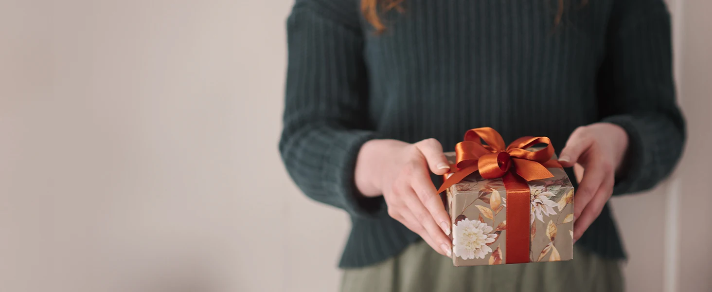 Woman in sweater holding decorative wrapped gift box with ribbon Christian Art Gifts