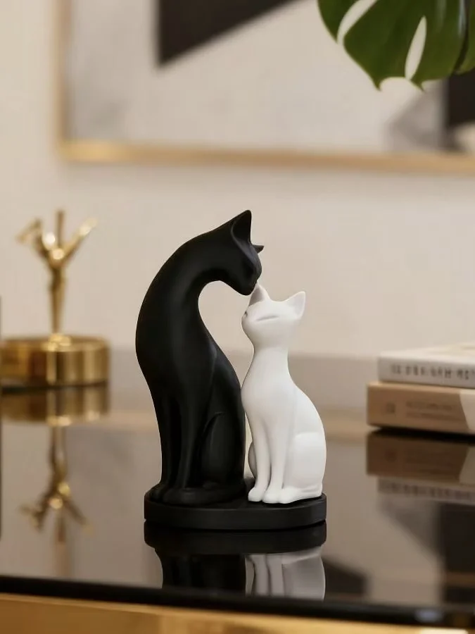 A black textured resin cat statue sitting in a calm yoga meditation lotus pose on a beige tablecloth next to a small white vase.