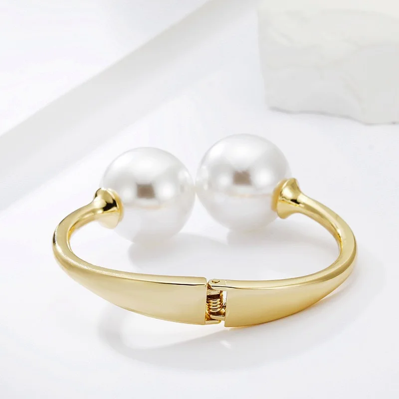 Gold-tone cuff bracelet with pearl ends for women – wide statement bangle with modern fashion appeal.