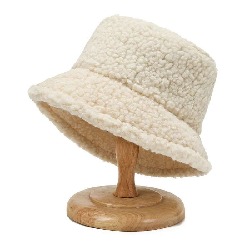 bob façon laine de mouton beige sur un porte chapeau en bois sur fond blanc