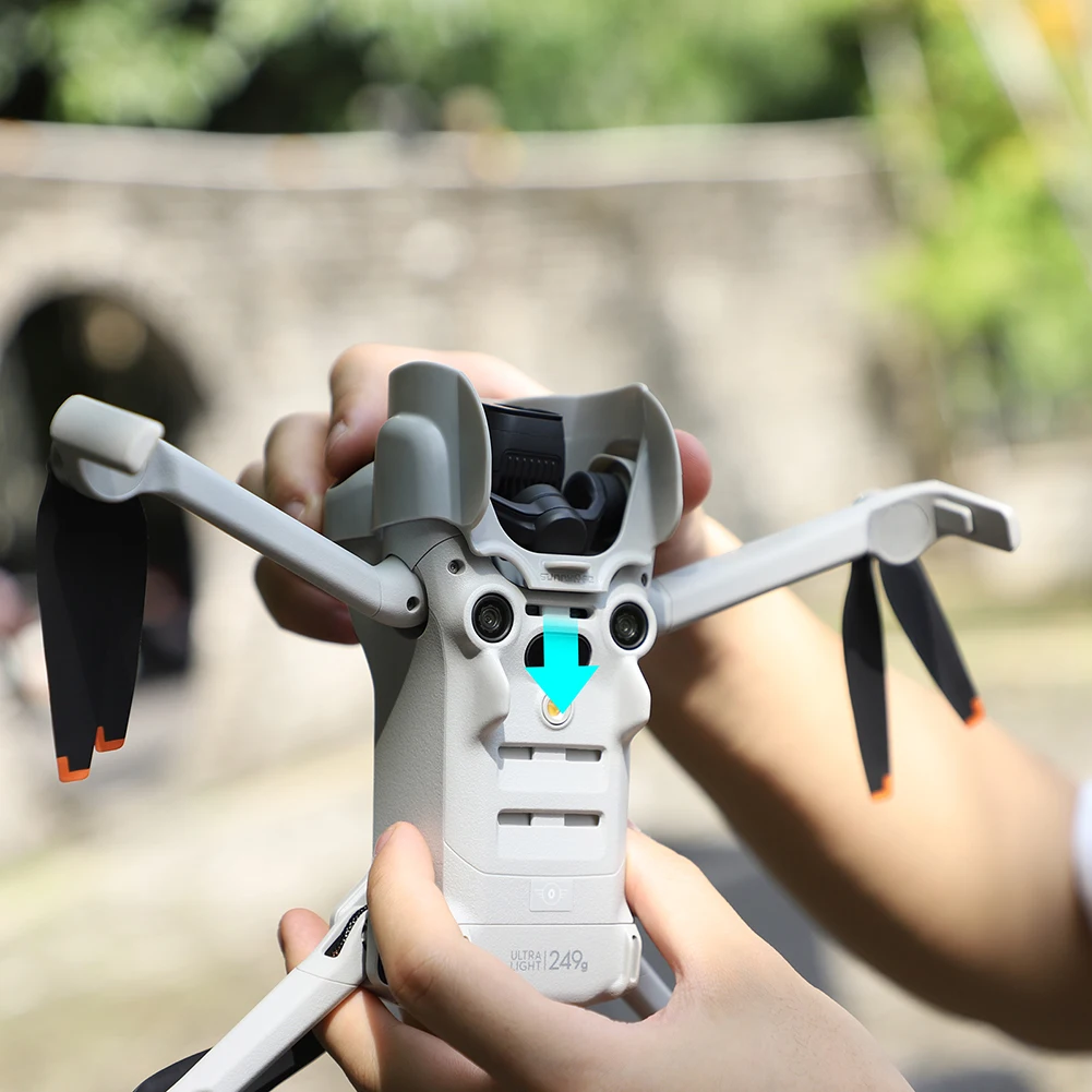 Installation du pare-soleil de protection sur l'objectif du DJI Mini 4 Pro, mains tenant le drone.
