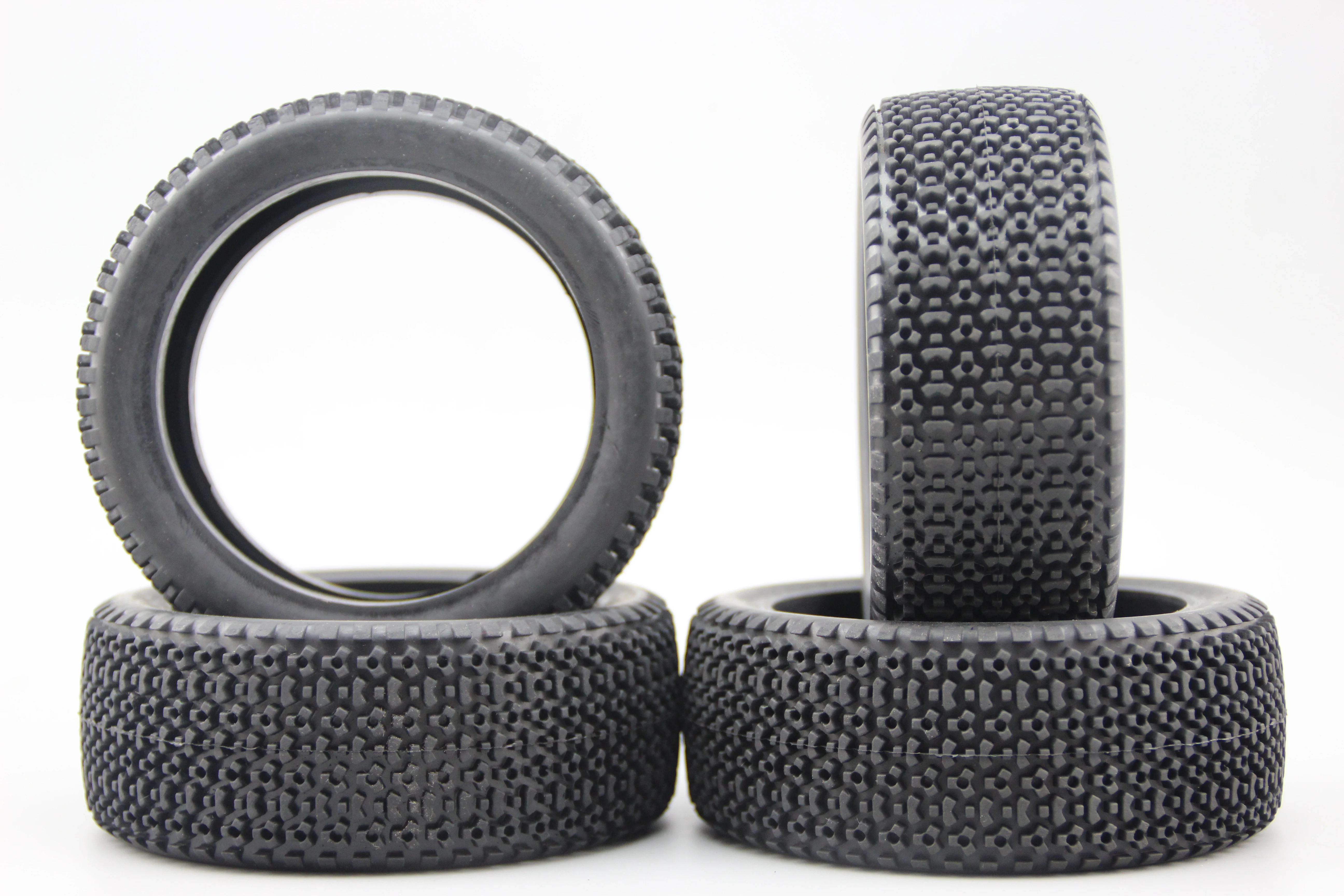 Pneus buggy RC 1/8 tout-terrain posés sur une surface rocheuse, montrant leur adhérence.