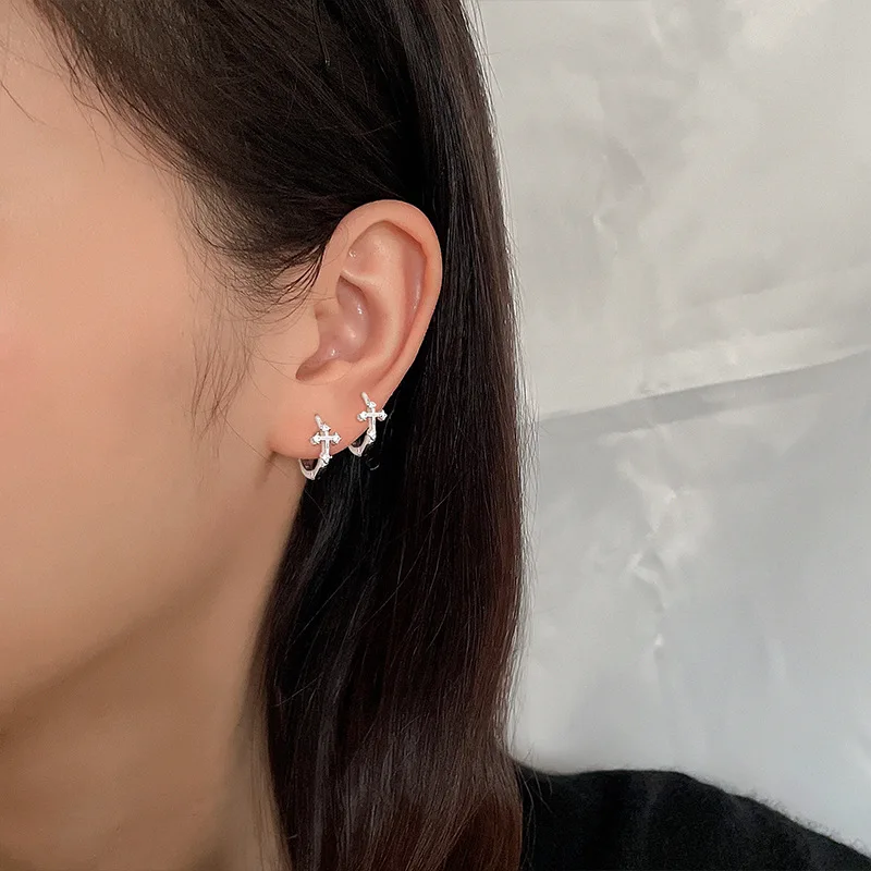 Close-up of a person wearing CIAXY silver cross hoop earrings with zircon detail on an ear.