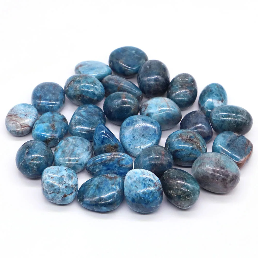 A collection of polished, smooth Moroxite tumbled stones, a blue-green variety of Apatite, scattered on a surface. These healing crystals are used for home decor and aquarium specimen displays.