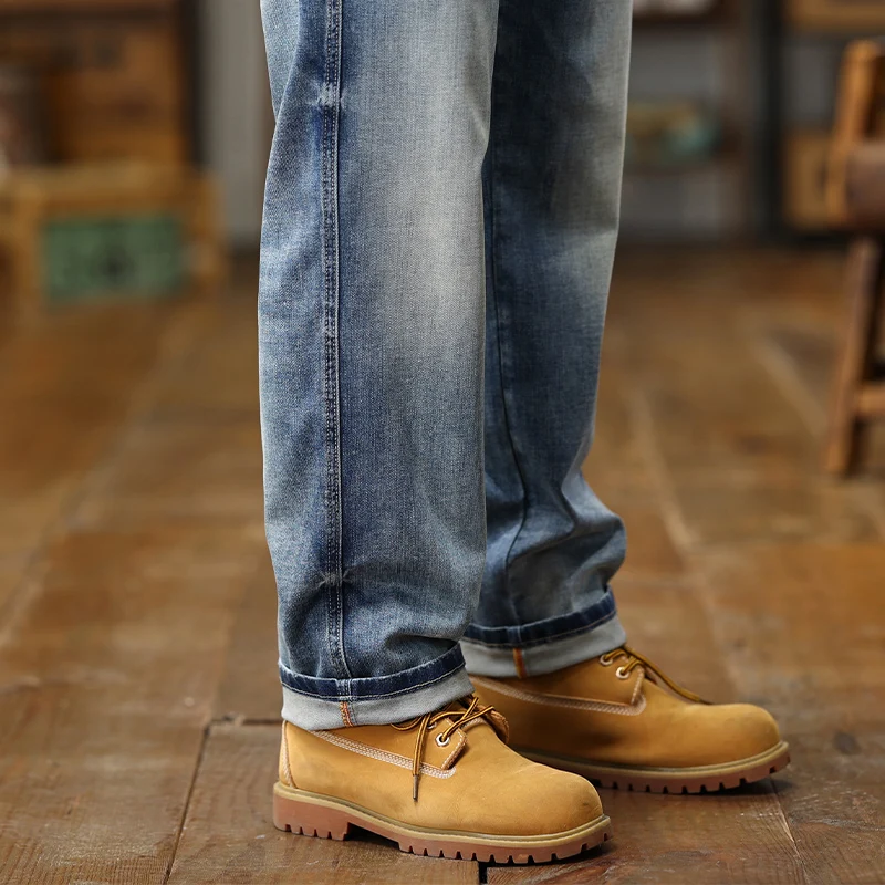 Bottes de travail en cuir tan de style Timberland, à laçage classique, avec des semelles en caoutchouc robustes, assorties à des pantalons à jambe large en jeans amples en denim bleu clair