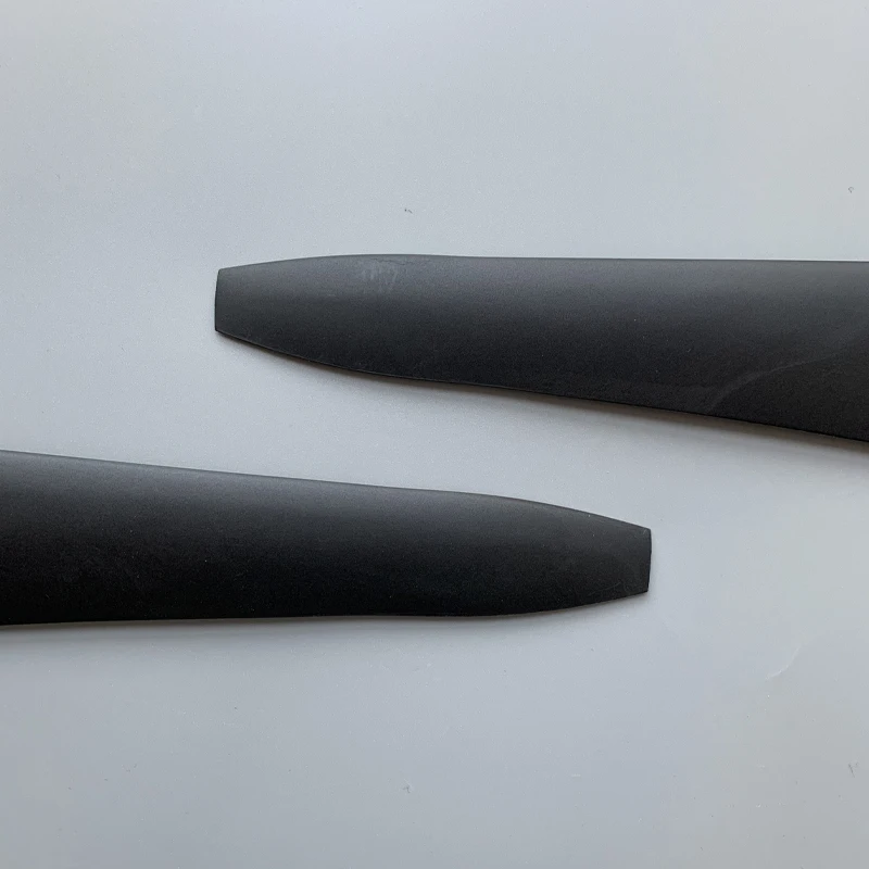 Pales d'hélice en nylon et fibre de carbone, une CW et une CCW, posées sur fond neutre.