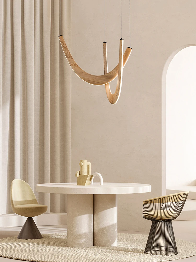 Minimalist dining area with a round white table, two modern chairs, soft beige curtains, and the Double Curve Wood Pendant Light overhead in a sunlit room.