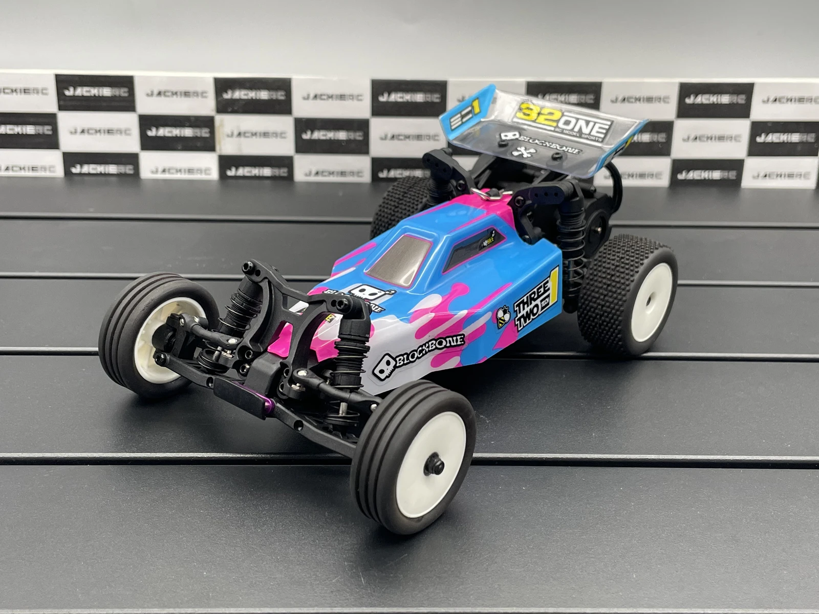 Voiture télécommandée crawler RC MB24 4WD 1/24 RTR bleue et rouge escaladant une pente rocheuse avec des suspensions actives.