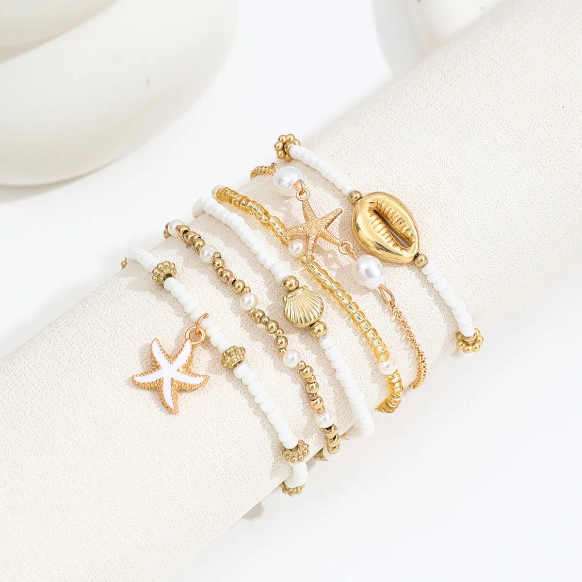 Conjunto de pulseiras vintage com miçangas empilhadas e detalhes de estrelas-do-mar e conchas. Acessórios elegantes para mulheres, perfeitos para o verão na praia._voghion.com