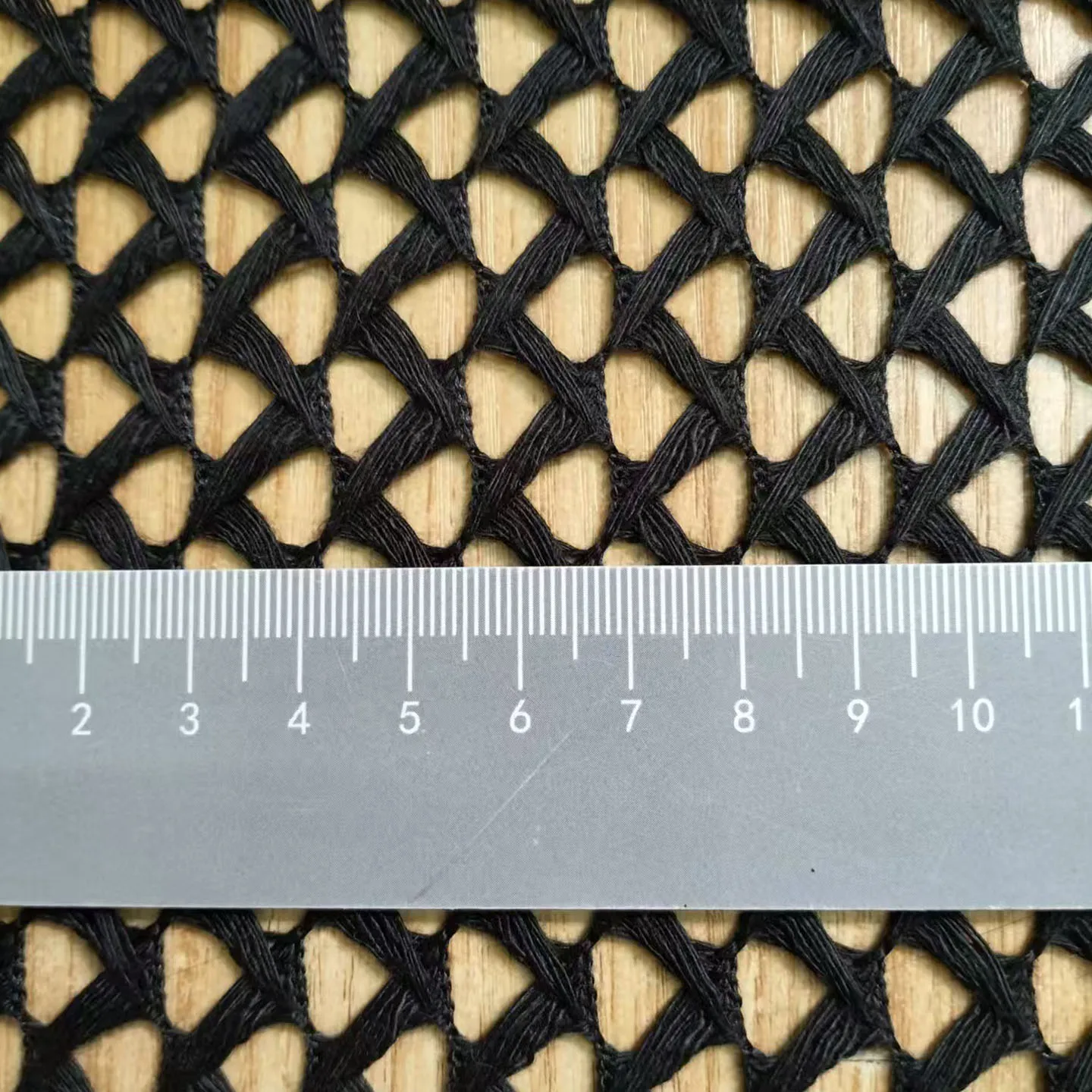 Tissu tulle noir 90x145cm pour masques réutilisables déplié, mesurant un yard, avec règle à côté pour l'échelle.