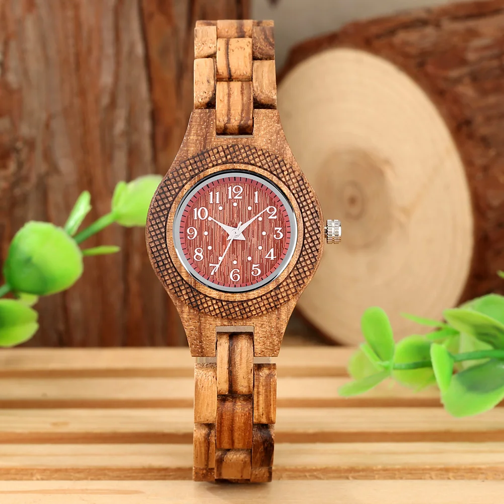 Elegantne puidust käekell naistele, kella punakaspruun sihverplaat ja peen puidust rihm, taustal puu ja lehed.